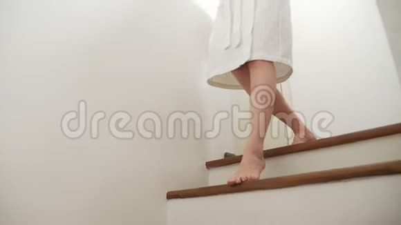 特写镜头女腿上升到木梯的顶部穿着晨衣的女人走上台阶视频的预览图
