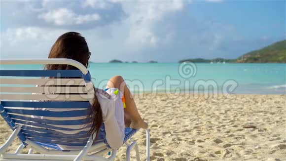 暑假的时候躺在沙滩上晒太阳的女人放松和享受慢动作视频的预览图
