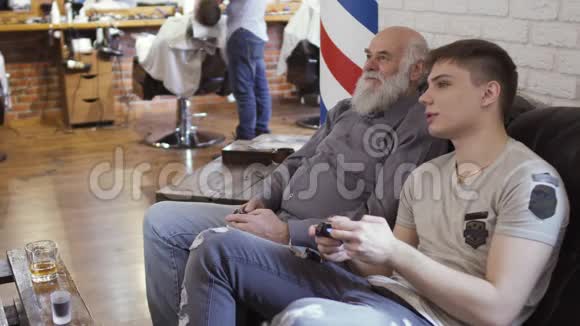 有成熟男人的年轻人在理发店玩电子游戏视频的预览图