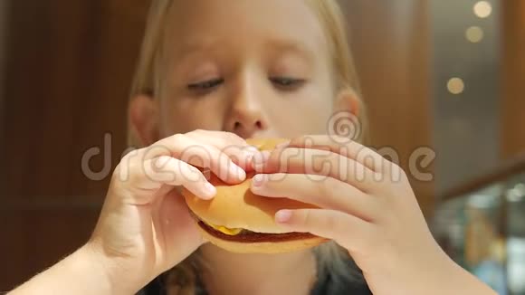 美丽快乐饥饿的女婴吃汉堡包快餐概念手里拿着不健康的汉堡三明治视频的预览图