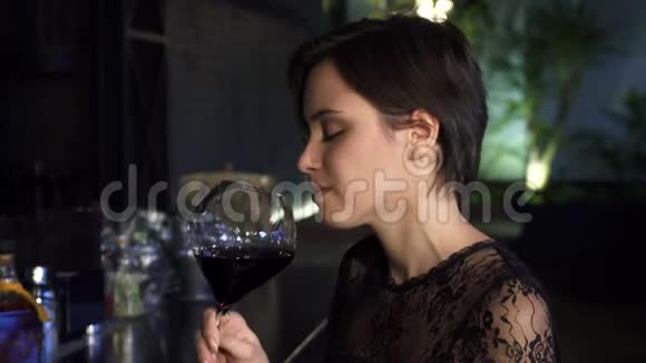 一位美丽的年轻黑发女子晚上在酒吧喝酒的特写镜头视频的预览图