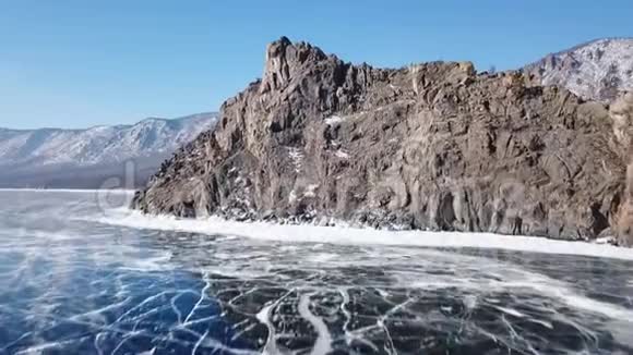 从上面捕捉到的美丽的深蓝冰纹理的贝加尔湖表面和海岸的空中透视视图视频的预览图