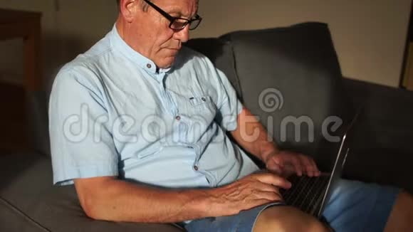 一个成熟的男人正在和一个坐在沙发上的努特贝克一起工作为养恤金领取人提供远程就业和网上银行服务视频的预览图