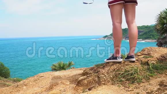 女孩旅行者站在热带海洋海岸的岩石边缘一个有沙滩的岛屿游客视频的预览图