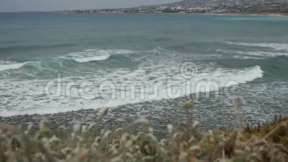 巨大的泡沫由蓝色水晶般清澈的海水在地中海海岸线上的城镇景观背景下形成视频的预览图