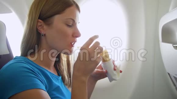 坐飞机的女人在湍流中女性在靠近窗户的地方吃三明治和喝酒视频的预览图