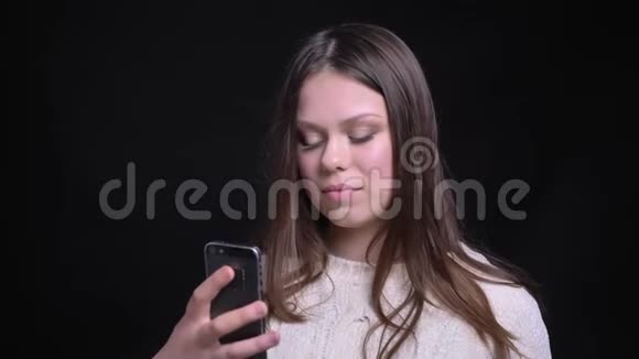 年轻漂亮的白种人女性在手机上自拍的特写镜头背景与黑色隔离视频的预览图
