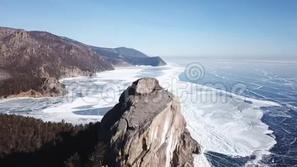 从上面捕捉到的美丽的深蓝冰纹理的贝加尔湖表面和海岸的空中透视视图视频的预览图