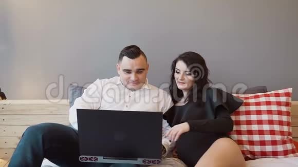男人和他美丽的怀孕妻子在家里的床上用他们的笔记本电脑家庭幸福2人视频的预览图