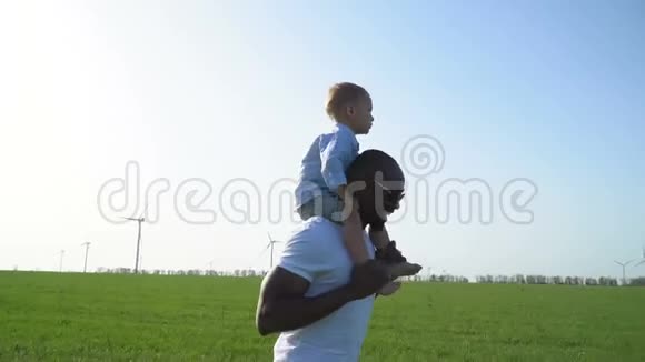 黑人穿过草地肩上扛着一个白人男孩视频的预览图