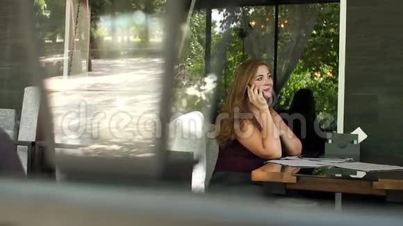 年轻的超重女孩坐在街头咖啡馆里打电话视频的预览图