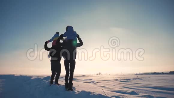 日落时幸福的家庭父亲母亲和两个孩子在大自然中玩着雪冬散步视频的预览图