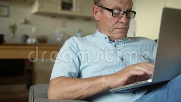 坐在厨房里用笔记本电脑工作的老人网上银行填写纳税申报表网上购物视频的预览图