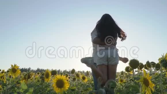 男人抱着女人恋爱中的情侣在向日葵的田野里转视频的预览图