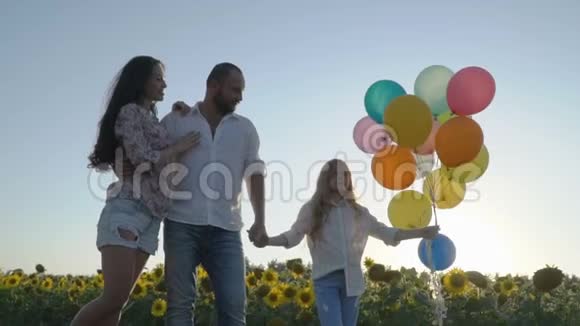 可爱的一家人带着气球在向日葵田散步视频的预览图