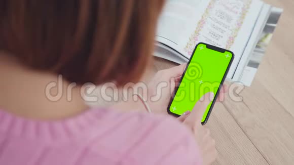 一位留着短发的年轻女子拿着绿色屏幕的智能手机视频的预览图
