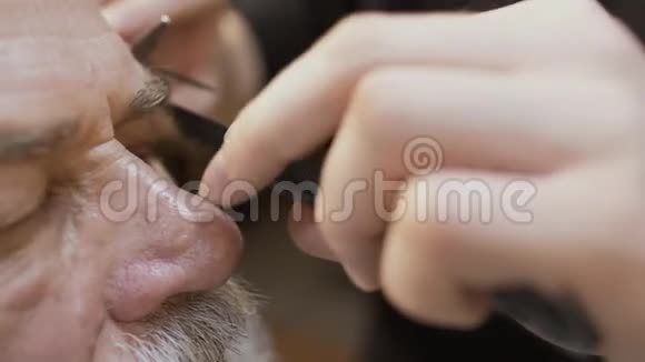 画家用剪刀剪成熟男人的眉毛视频的预览图