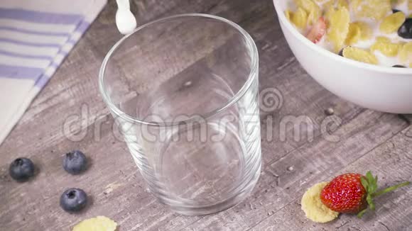 玻璃杯中的慢动作在上面的一碗玉米片旁边倒一杯饮料视频的预览图