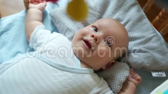 一个三个月大的婴儿躺在床上一个孩子抬头微笑他很活跃拉着他的手和腿打开视频的预览图