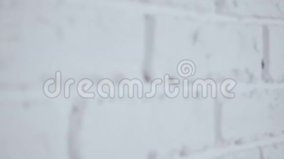 一个美丽悲伤的女人在白色砖墙附近摆姿势视频的预览图