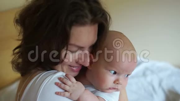 年轻的母亲把孩子抱在卧室里一个女人小心翼翼地拥抱一个三个月大的婴儿母亲节视频的预览图