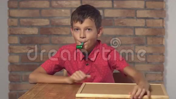 坐在书桌前的孩子拿着一张挂图背景是红砖墙上面写着生日快乐视频的预览图