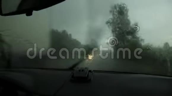 在恶劣的雨天驾驶在汽车行驶过程中通过挡风玻璃观看乡村道路窗外的雨滴视频的预览图