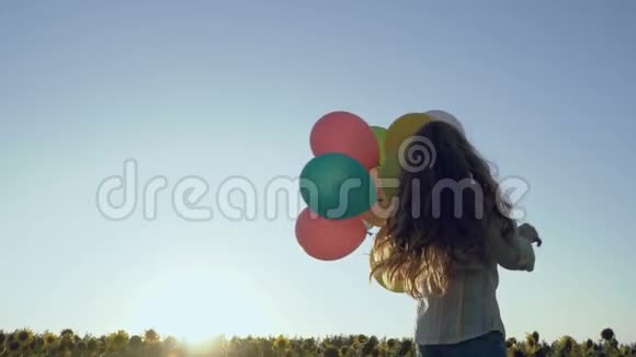 快乐的小女孩带着气球在向日葵田盘旋视频的预览图