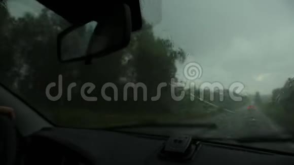 在恶劣的雨天驾驶在汽车行驶过程中通过挡风玻璃观看乡村道路窗外的雨滴视频的预览图
