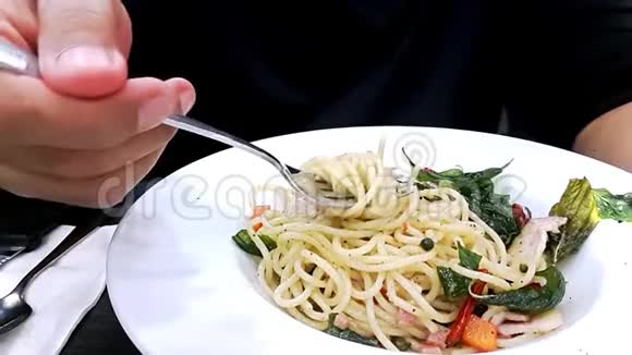 男人手捻叉子在桌子上白色背景上吃辛辣的意大利面视频的预览图