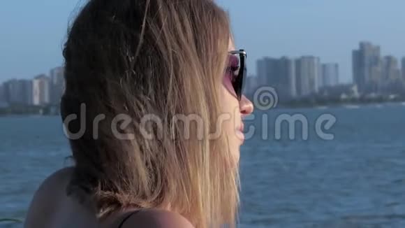 一位美丽快乐的白种人年轻女士戴着太阳镜欣赏美丽的日落的肖像视频的预览图