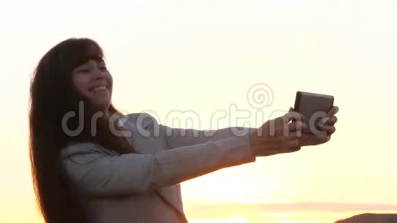 美丽的商务女性在日落的背景下使用手机拍摄一张自拍照片视频的预览图