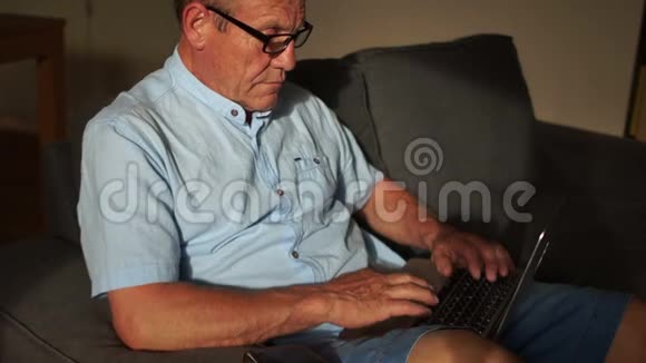一位老人用互联网和笔记本电脑从家里支付账单网上银行网上银行视频的预览图