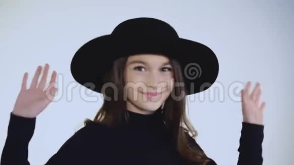 白色背景镜头下戴帽子跳舞的快乐女孩的肖像视频的预览图
