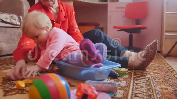 小女孩和她的祖母坐在地板上玩玩具和交流视频的预览图
