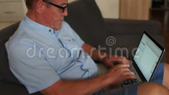 在家做笔记本电脑的老人他穿着一件蓝色衬衫戴着眼镜看不见远程就业自由职业者视频的预览图