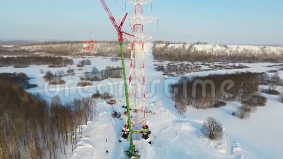 起重机把高塔的一部分吊在冬日的树林上视频的预览图
