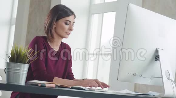 女人坐在电脑前的显示器上打印一段文字微笑着视频的预览图