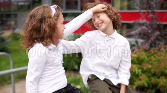 初恋女孩和男孩愉快地聊天女孩抚摸男孩的头男孩笑了视频的预览图