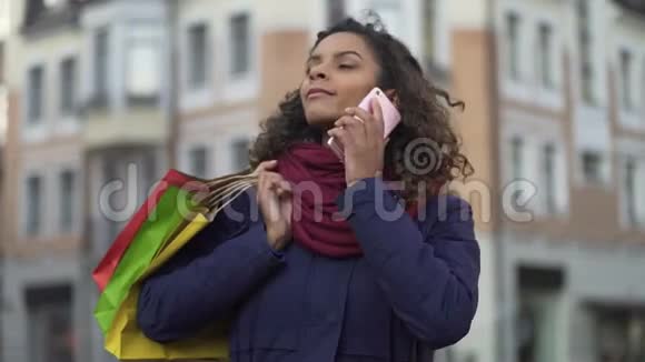 带着购物袋的女人打电话给女性朋友告诉他们商店的折扣视频的预览图