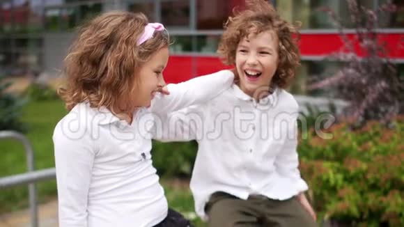 学校的友谊一对少年一男一女正坐在栏杆上女孩正牵着她的手在栏杆上视频的预览图