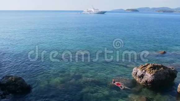 年轻女子在蓝色的热带水中浮潜穿着红色泳衣在地平线上乘坐游轮旅行概念视频的预览图