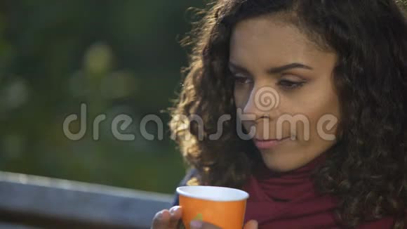 年轻的卷发女士在户外享受最喜欢的早间咖啡视频的预览图