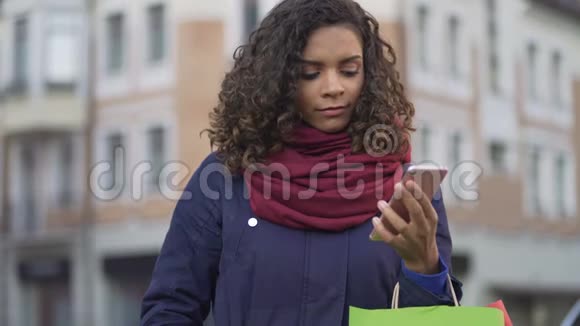 网上挑选礼物的漂亮女人在智能手机上浏览网店销售视频的预览图