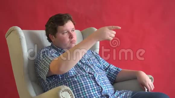 年轻的经理坐在椅子上手指着红色的背景视频的预览图