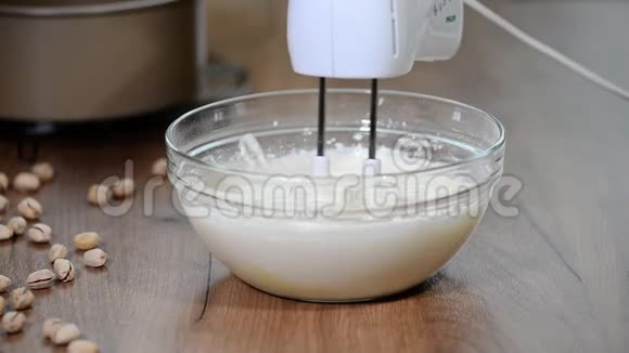 厨师用搅拌器将奶油倒入碗中视频的预览图