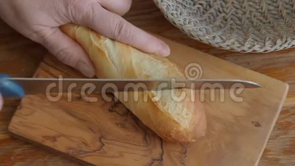 用刀在木切割板上切割长面包视频的预览图