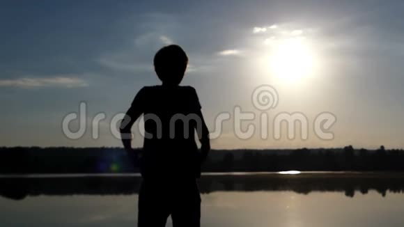 黄昏时分一个金发碧眼的人在湖岸上快乐地举手视频的预览图