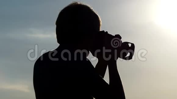 年轻人站在森林湖边夏天看着他的相机视频的预览图