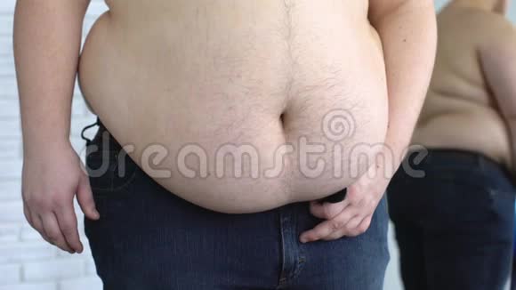 超重的人在收紧牛仔裤腰带的同时还会保持肥胖的胃视频的预览图